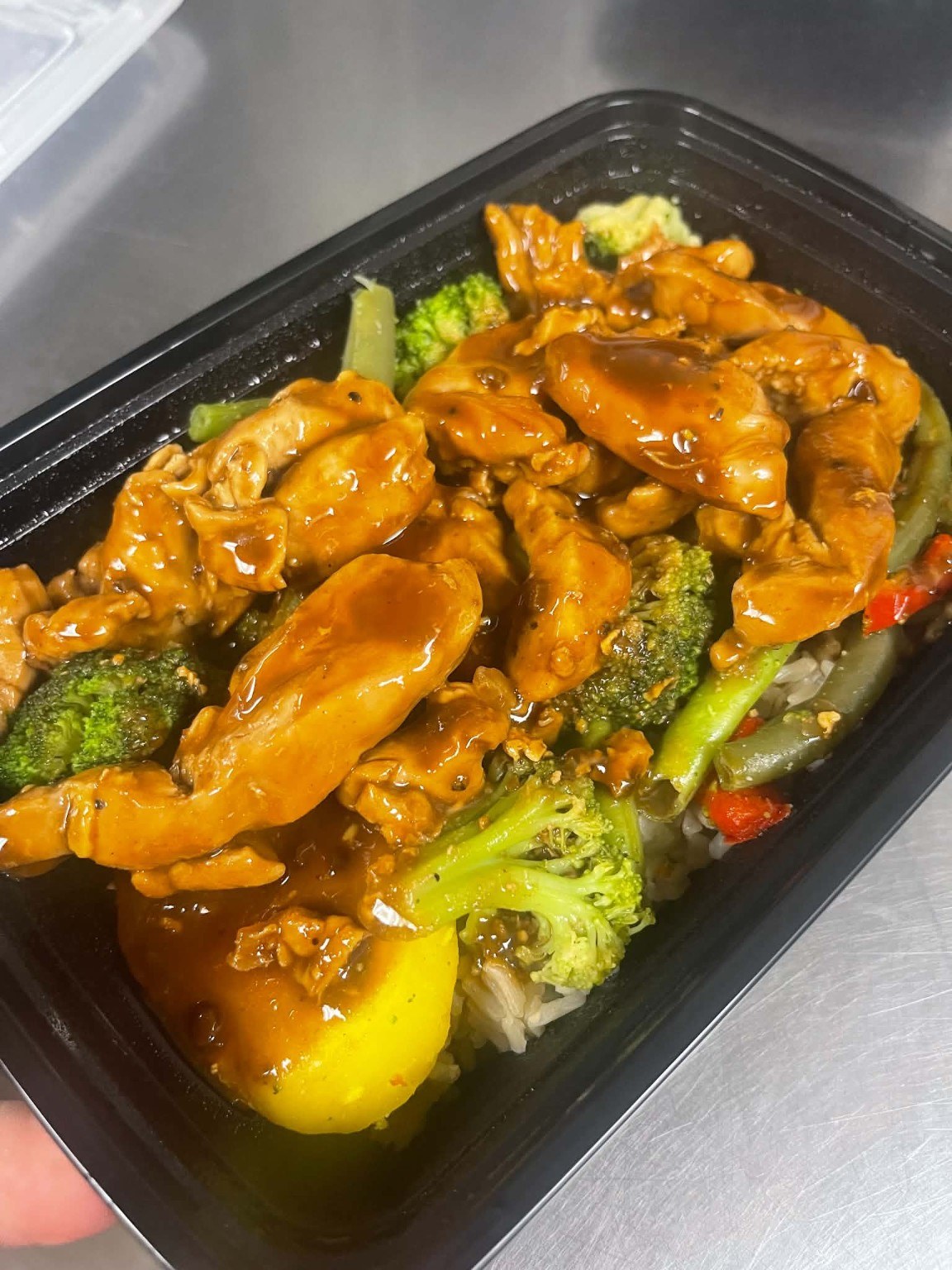Chicken with broccoli and colorful vegetables over rice, prepared in a meal container