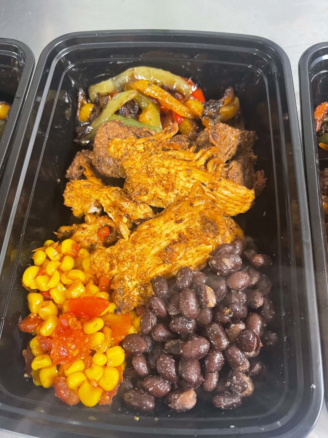 Seasoned meats, peppers, corn and black beans in a meal container
