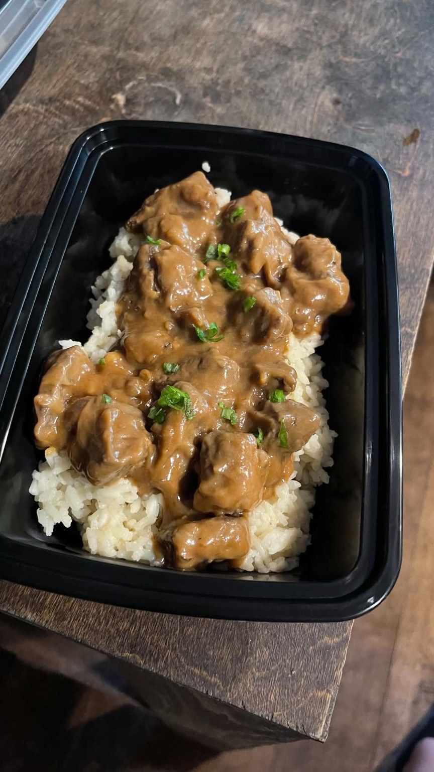 Meat and gravy over white rice, garnished with green onions