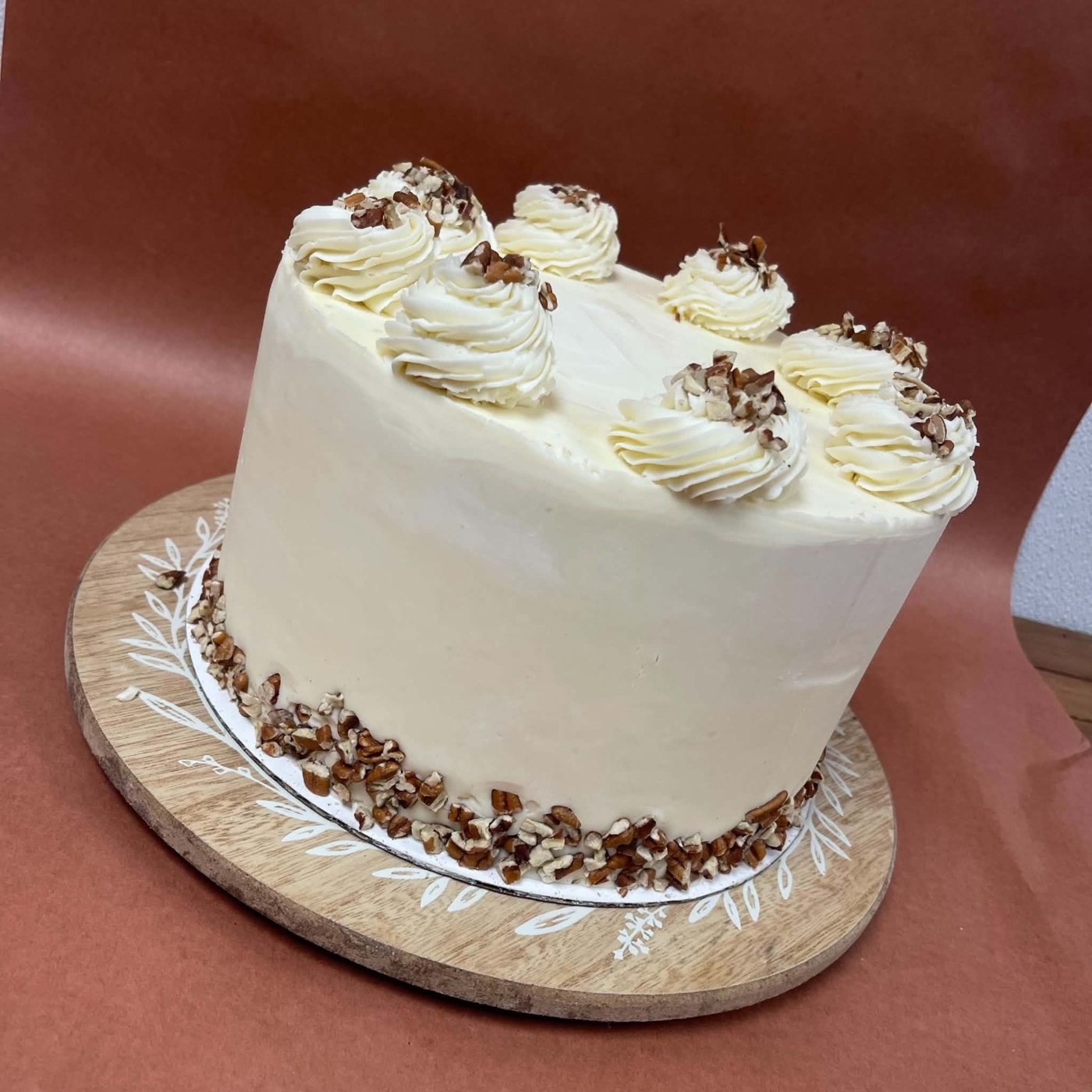 A white-frosted cake with piped swirls and chopped nuts